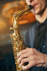 Obraz premium Young man in a suit hold a saxophone musical instrument