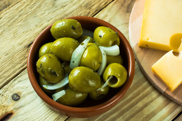 Jumbo gordal olives with herbs, cheese on wood background, top view