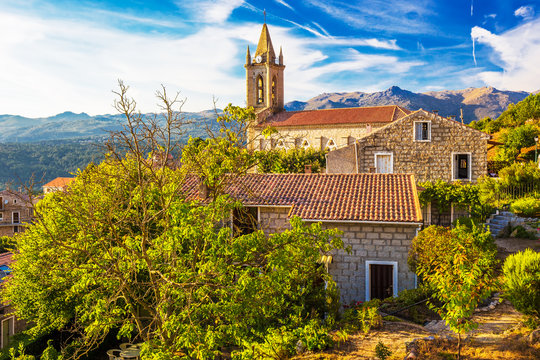 Church in Zonza village with typical stone houses during sunset, Corsica, France