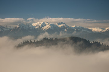 Snowy Tatra mountains over clouds, Poland