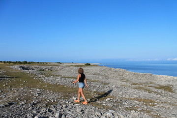 En ensam tjej går på stenstranden