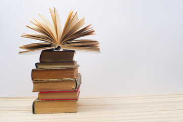 Open book, stack of hardback books on wooden table. Back to school. Copy space
