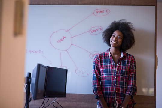 African American Woman Writing On A Chalkboard In A Modern Offic