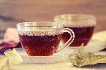 Hot cup of tea with some autumn leaves on a rustic wood table top background