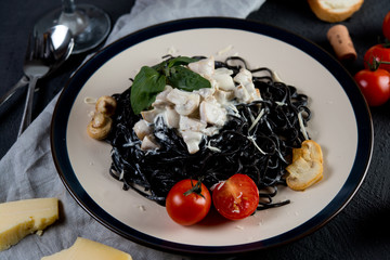 Traditional Italian dish. Spaghetti with ink of a cuttlefish and creamy sauce with mushrooms
