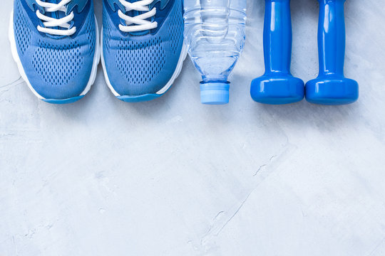Flat lay sport shoes, bottle of water and dumbbells