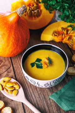 Cream pumpkin soup with fresh herbs and crackers on dark wooden background. Healthy food. Selective focus. Top view.