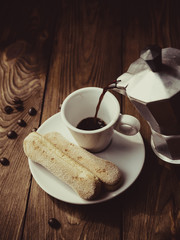 Cup of hot espresso, moka pot and cookies on the wooden table