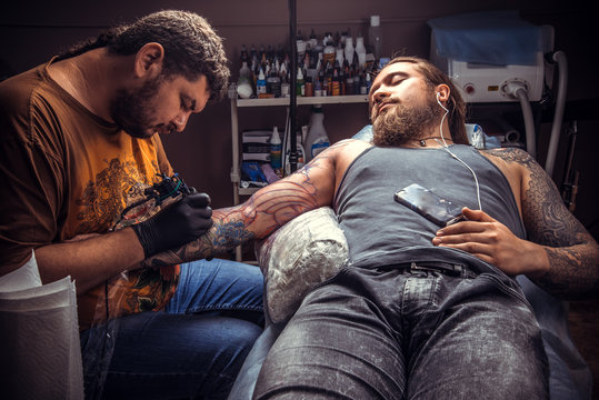 Professional tattoo artist makes tattoo pictures in tattoo parlor