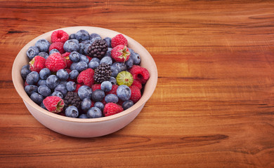 Brown ceramic plate with berries on the wooden table with clipping path