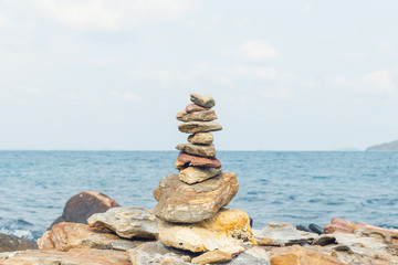 Fototapeta na wymiar Stones balance, pebbles stack over blue sea in Thailand. Blue sky on sunny in summer.