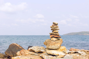 Fototapeta na wymiar Stones balance, pebbles stack over blue sea in Thailand. Blue sky on sunny in summer.