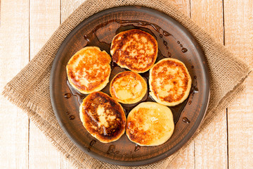 Cottage cheese pancakes with honey on brown ceramic plate