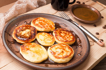Cottage cheese pancakes with honey on brown ceramic plate