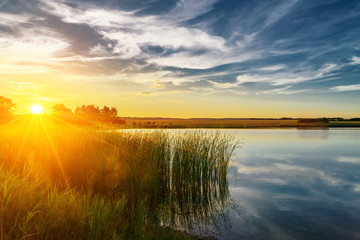 Fototapeta na wymiar Summer sunset at the river with blue sky green trees and water w