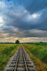 Fototapeta premium Dramatic landscape with heavy clouds and railroad