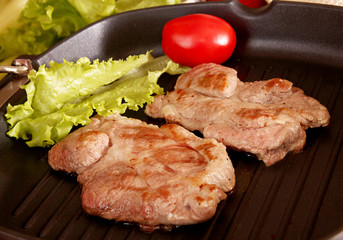 Two pieces of of grilled pork steaks over on frying grill pan