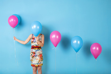 Woman and helium balloons on a blue background.
