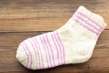 Fototapeta na wymiar Handmade knitted woolen kid's socks on rustic wooden background.