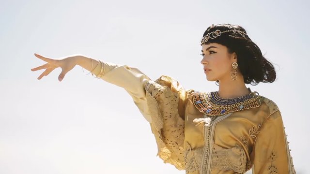 Beautiful woman with fashion make-up and hairstyle like Egyptian queen Cleopatra outdoors against sky