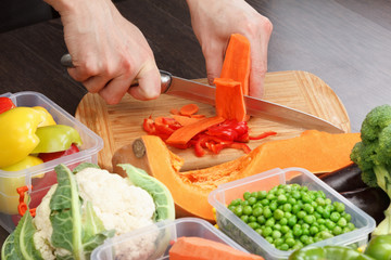 Chef cutting carrot for cooking. Stock up on winter food.