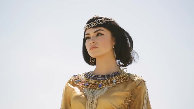 Beautiful woman with fashion make-up and hairstyle like Egyptian queen Cleopatra outdoors against desert windy weather