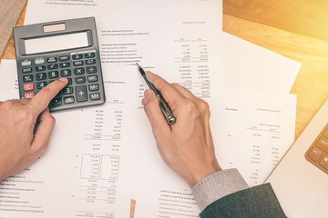 Businessman hand working with balance sheet paper. Photo with sunlight filter effect.