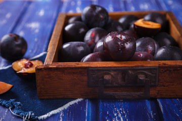 Plums in wooden box on vintage blue background.selective focus.