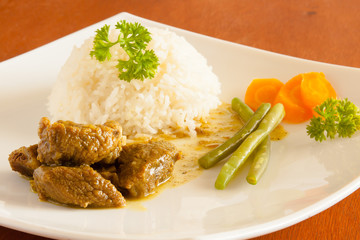 Curried Goat served with white rice, string beans and sliced carrots. 