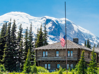 Log cabin in front of Mount Rainier with American Flag flying at half-mast
