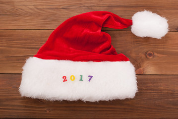 Obraz na płótnie Canvas Hat of Santa Claus and the numbers 2017 on the wooden background.