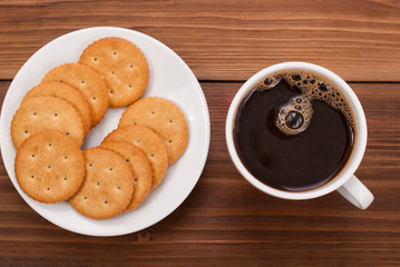 Cup and cookies on the plate on a wooden background.