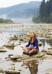 woman meditating sitting on stone in quiet location