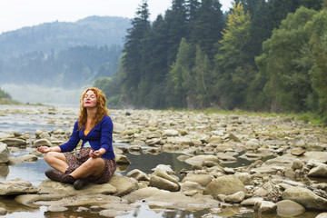 woman meditating sitting on stone in quiet location