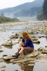 woman resting on the rocks in the middle of mountain lake
