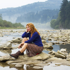 woman resting on the rocks in the middle of mountain lake