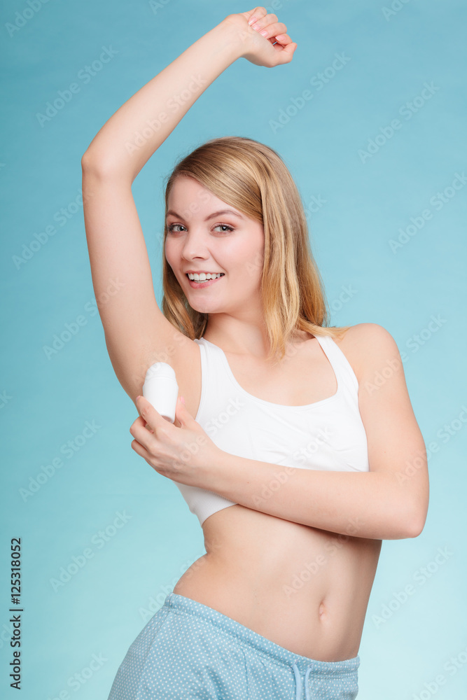 Wall mural Girl applying stick deodorant in armpit.