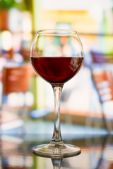 Red wine glass against blurred restaurant