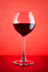 Red wine glass against red background