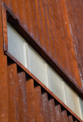 Rusted, Corrugated Metal Wall with Row of Textured Glass Blocks Viewed from an Angle