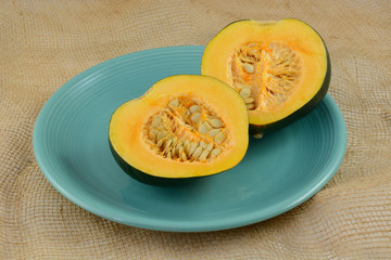 Raw uncooked acorn squash halves with seeds on blue plate