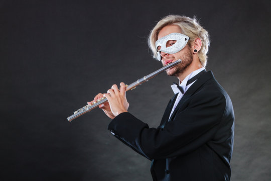 man in carnival mask playing flute