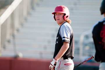 High school baseball player with long hair batting. © tammykayphoto