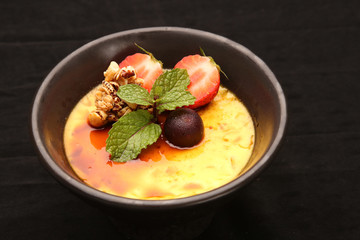 Creme brulee - traditional french vanilla cream dessert with strawberries and mint leaf on the top