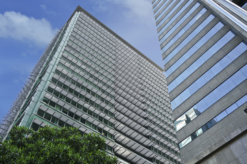 Obraz premium Perspective and underside angle view to textured background of modern glass building skyscrapers with blue sky.