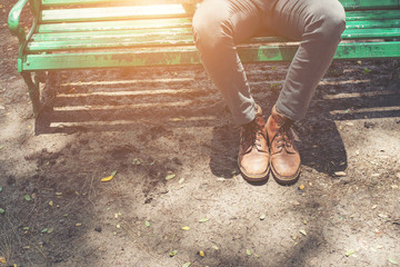 Hipster guy sitting on bench with  jeans and brown chamois shoes