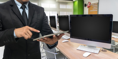 Businessman using the tablet on empty computer room background,