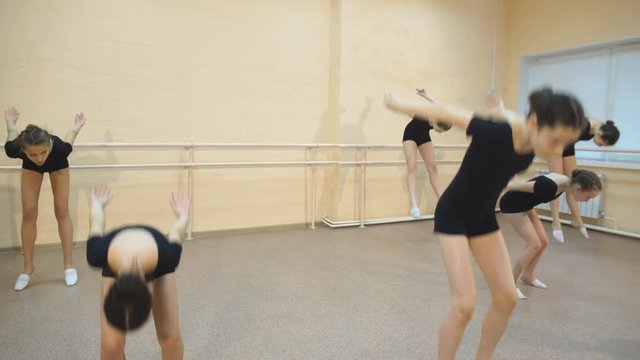 group of four young ballerinas standing in row and practicing ballet