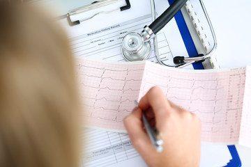 Doctor hands with cardiogram chart on clipboard pad