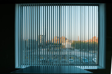 City view  through the vertical blinds window decoration in interior of dark room
